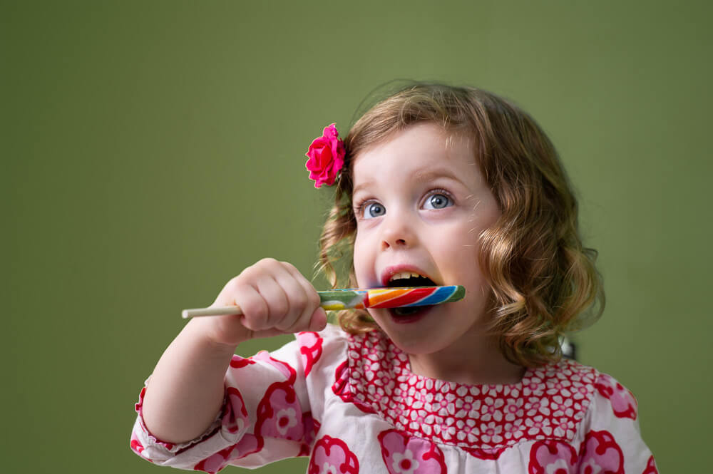 Portrait of cute girl enjoying a lollipop by Nick Perry Photography