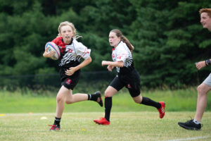Young female rugby player running with the ball