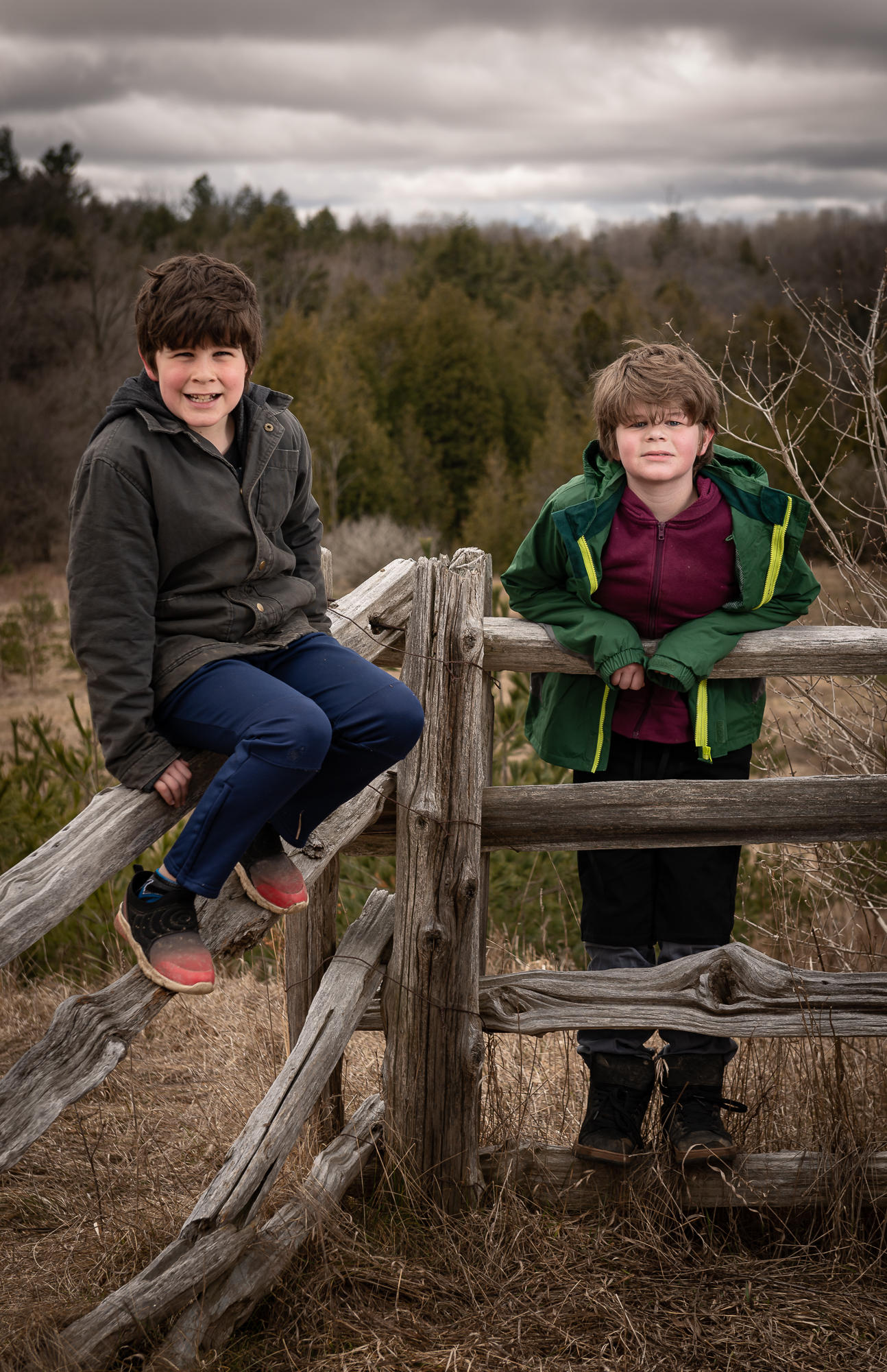 Two boys standing by a fence