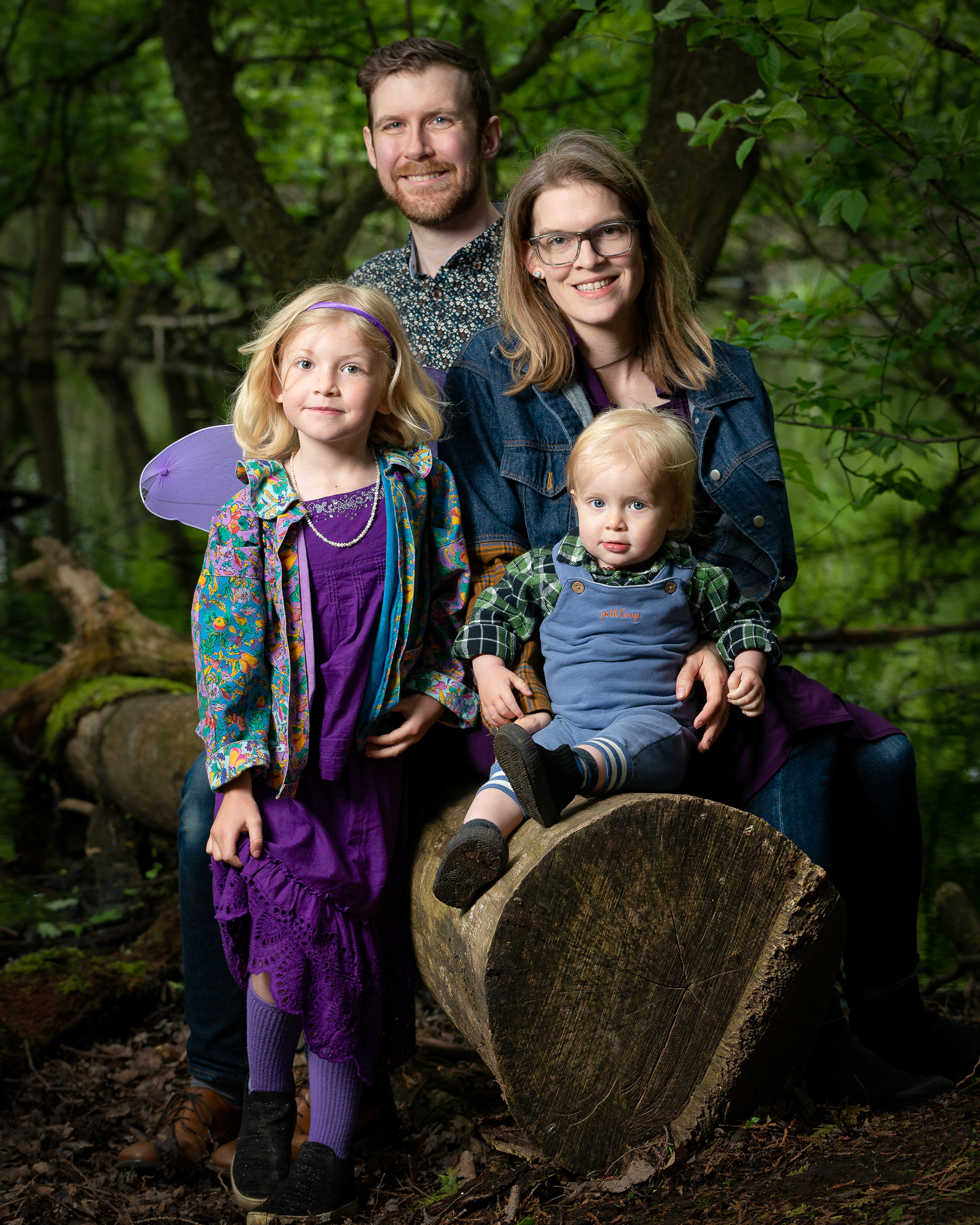 A family sitting in on a log in the forest